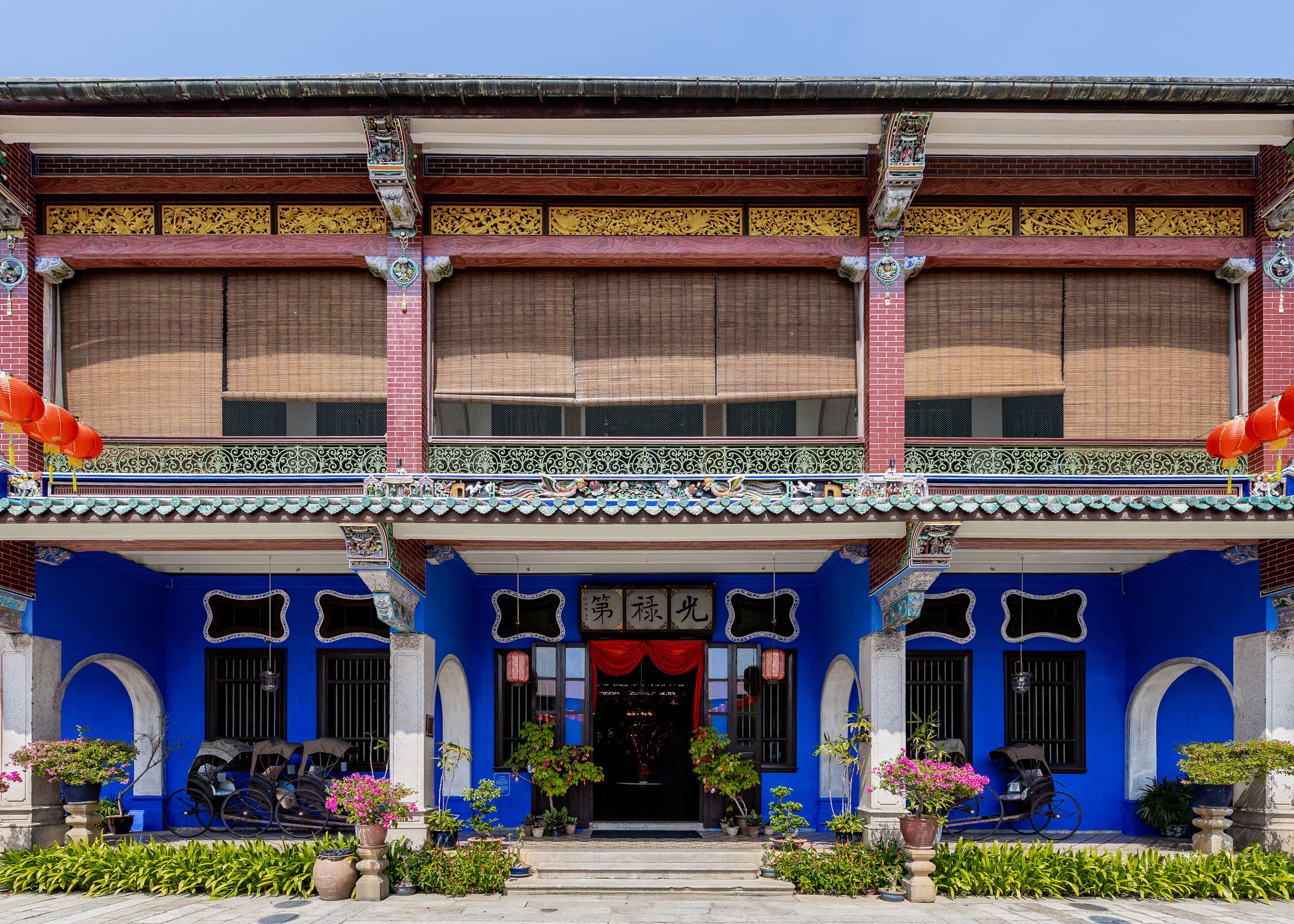 Indigo facade of Cheong Fatt Tze Mansion with lanterns and rickshaws, George Town